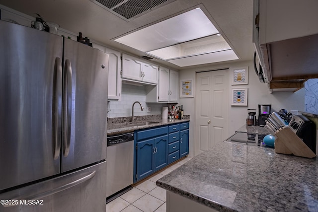 kitchen featuring decorative backsplash, blue cabinetry, appliances with stainless steel finishes, a sink, and light tile patterned floors