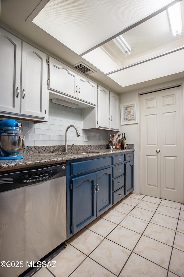 kitchen with light tile patterned floors, decorative backsplash, stainless steel dishwasher, a sink, and visible vents
