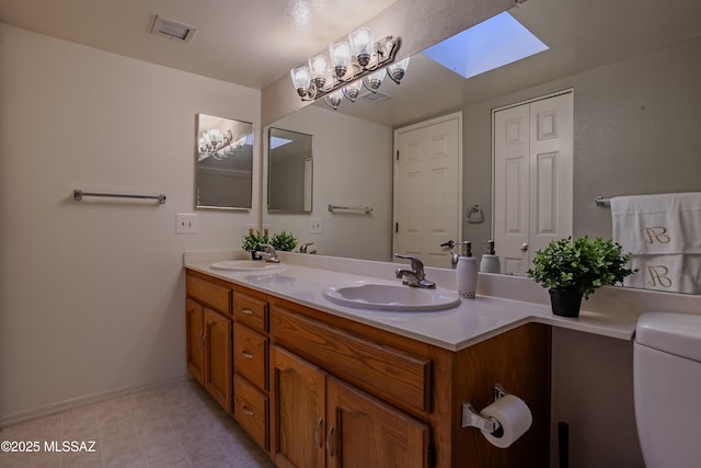 full bath featuring visible vents, a sink, double vanity, and a skylight