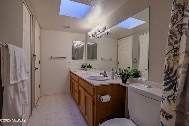 full bathroom featuring double vanity, a sink, toilet, and a skylight