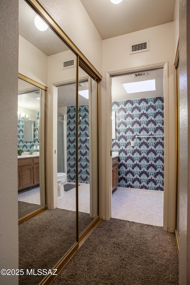 hall with tile patterned floors, visible vents, and carpet floors