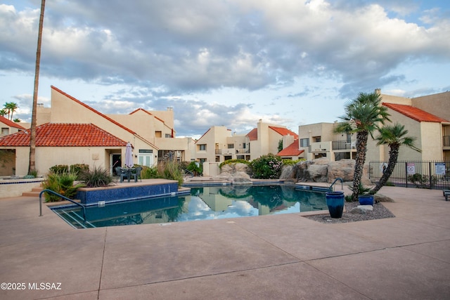 community pool with a residential view, fence, and a patio