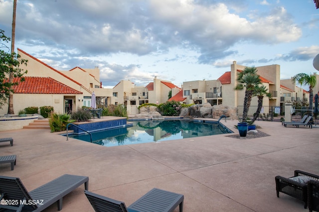 community pool with a residential view, fence, and a patio