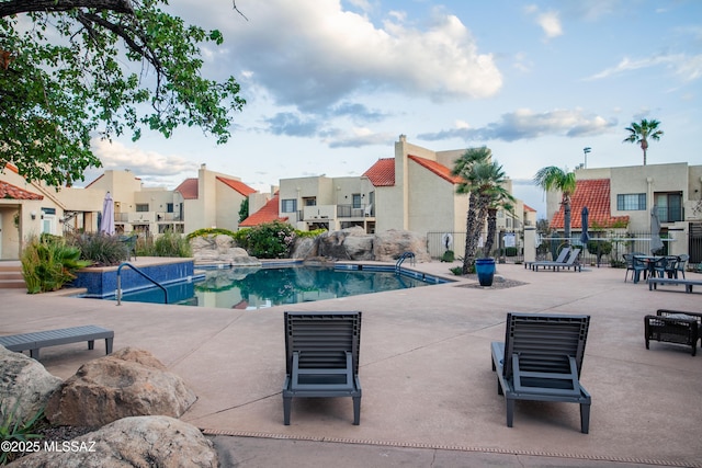 pool with fence, a patio area, and a residential view