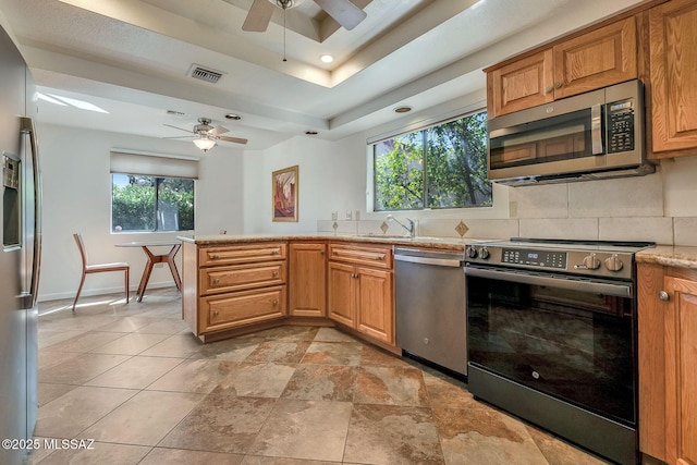 6091 N Golden Eagle Dr, Tucson, AZ 85750 - kitchen with a peninsula, a raised ceiling, stainless steel appliances, decorative backsplash, and ceiling fan