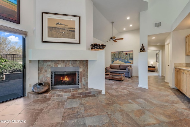 6091 N Golden Eagle Dr, Tucson, AZ 85750 - unfurnished living room with visible vents, baseboards, a high ceiling, a tiled fireplace, and ceiling fan