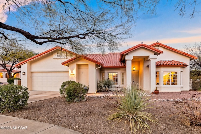 mediterranean / spanish house featuring stucco siding, a tile roof, concrete driveway, and an attached garage