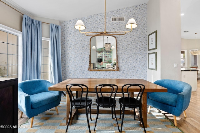 dining room featuring lofted ceiling, visible vents, wood finished floors, and wallpapered walls