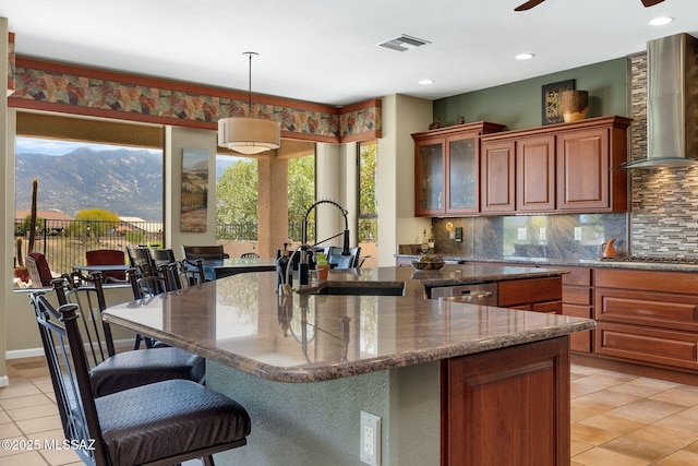 kitchen featuring light tile patterned flooring, a sink, wall chimney range hood, and decorative backsplash
