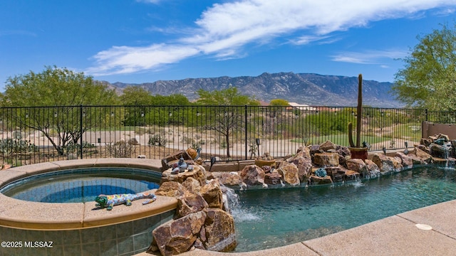 view of swimming pool with a mountain view, an in ground hot tub, and fence