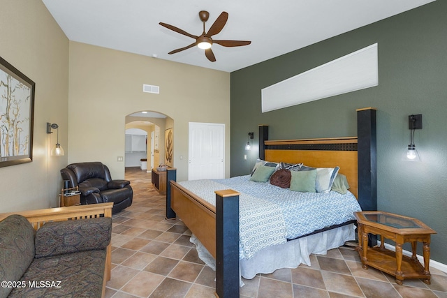 bedroom featuring visible vents, arched walkways, tile patterned floors, a ceiling fan, and a high ceiling