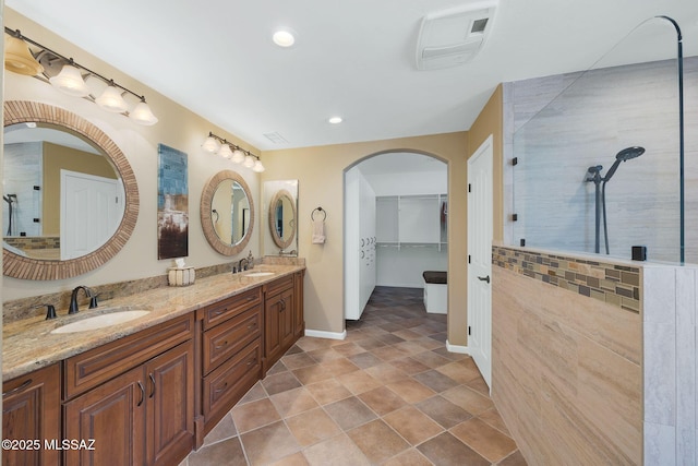 full bathroom featuring baseboards, visible vents, a walk in shower, and a sink