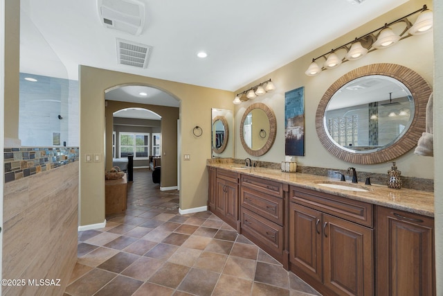 full bath with baseboards, visible vents, a walk in shower, and a sink