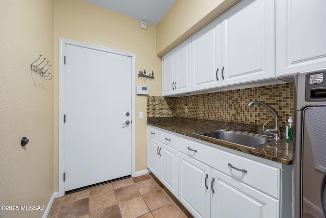 clothes washing area with baseboards, cabinet space, and a sink