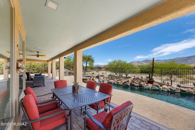 view of patio with a fenced in pool, a mountain view, a ceiling fan, outdoor dining space, and fence