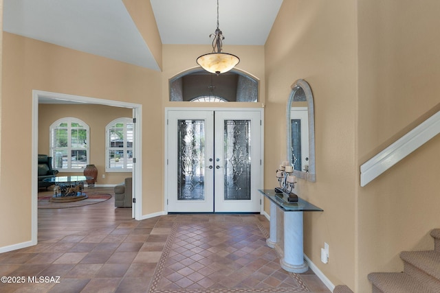 foyer entrance featuring a towering ceiling, french doors, baseboards, and stairs