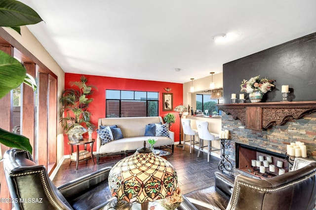 living room with baseboards and a stone fireplace