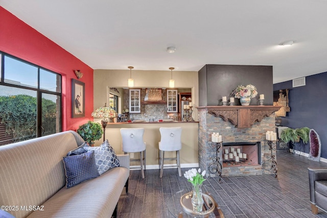 living room featuring wood finished floors, baseboards, a fireplace, and visible vents