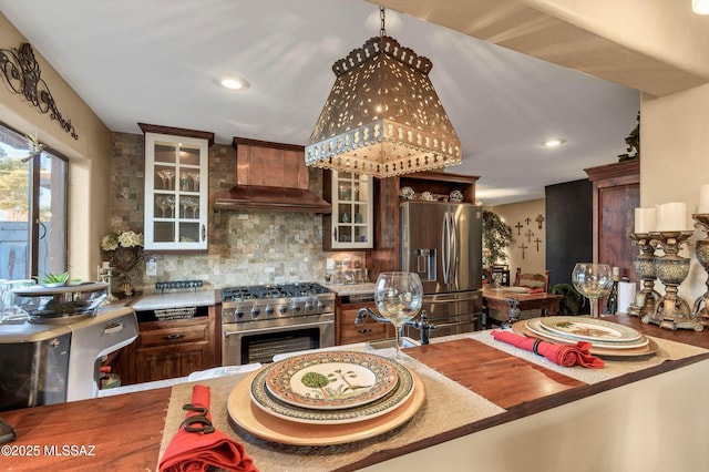 kitchen with custom range hood, tasteful backsplash, appliances with stainless steel finishes, and glass insert cabinets