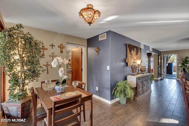 dining room with baseboards, visible vents, an inviting chandelier, and wood finished floors