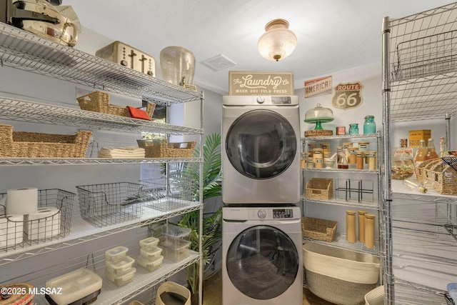 clothes washing area with visible vents, laundry area, and stacked washing maching and dryer