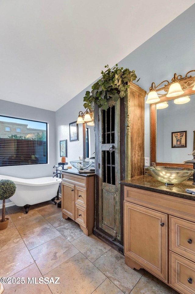 full bathroom with a sink, a freestanding tub, and two vanities