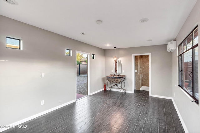 spare room with dark wood finished floors, baseboards, and an AC wall unit