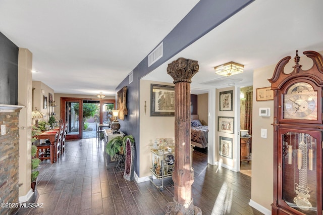 hallway featuring dark wood-style flooring, baseboards, and visible vents