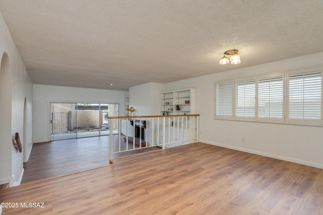 538 N Dodge Blvd, Tucson, AZ 85716 - empty room featuring arched walkways, a textured ceiling, baseboards, and wood finished floors
