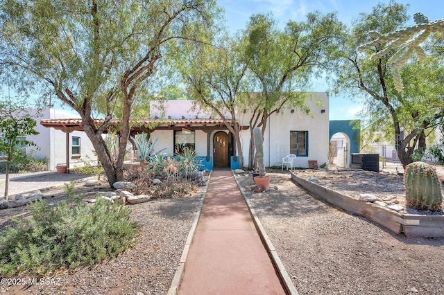 view of front of house with stucco siding, a gate, and central air condition unit