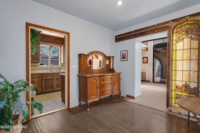 hall with baseboards, light wood-style flooring, and a sink
