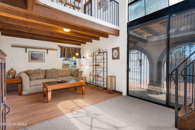 living area featuring a high ceiling, wood finished floors, beam ceiling, and a wealth of natural light