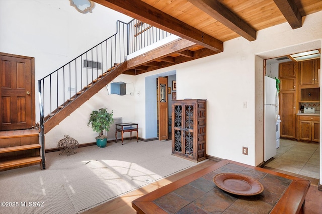 unfurnished living room with carpet, baseboards, stairway, beam ceiling, and wood ceiling