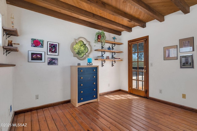 spare room with baseboards, wooden ceiling, beam ceiling, and wood-type flooring