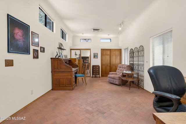 office space featuring a wealth of natural light, brick floor, and visible vents