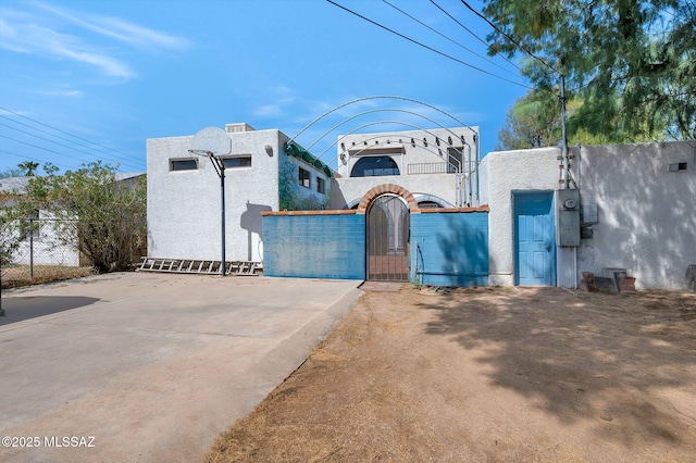 view of front of property featuring stucco siding, a gate, and fence