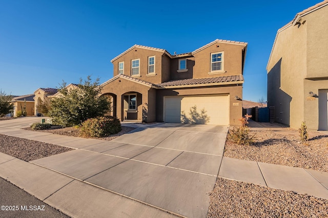 mediterranean / spanish home with a tile roof, stucco siding, an attached garage, and concrete driveway