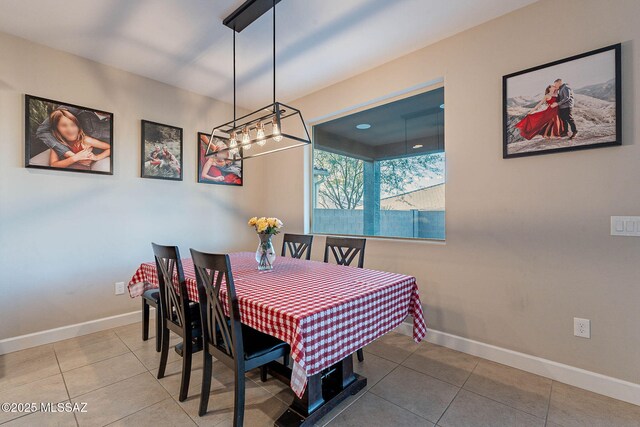 tiled dining room featuring baseboards and a notable chandelier