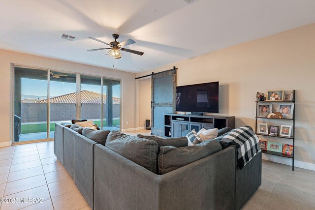 living room with light tile patterned flooring, visible vents, a barn door, and a ceiling fan