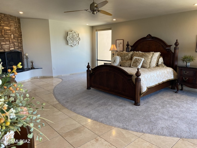 bedroom with ceiling fan, light tile patterned flooring, recessed lighting, light carpet, and a fireplace