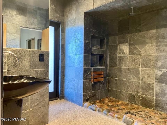 bathroom with a tile shower and a sink