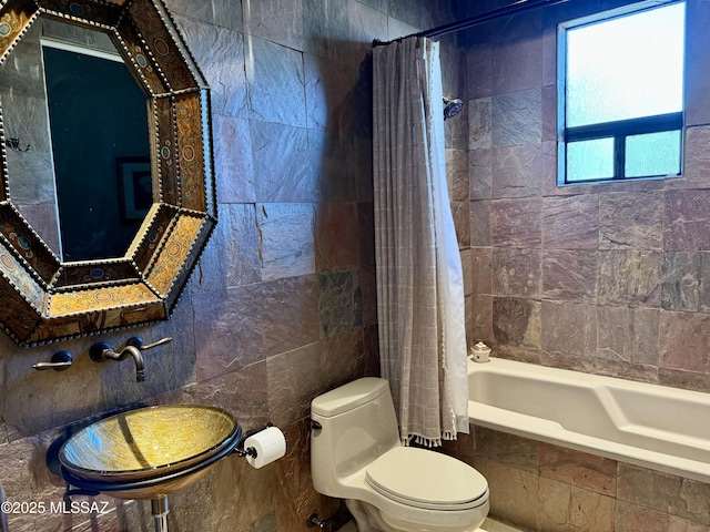 bathroom with toilet, tile walls, and tiled shower / bath