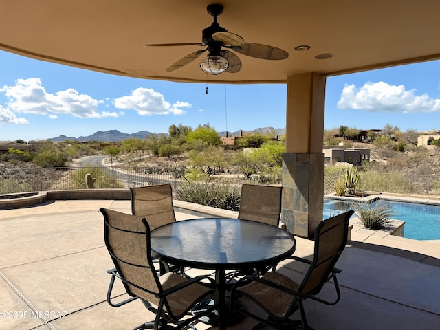 view of patio with a mountain view, ceiling fan, fence, and an outdoor pool