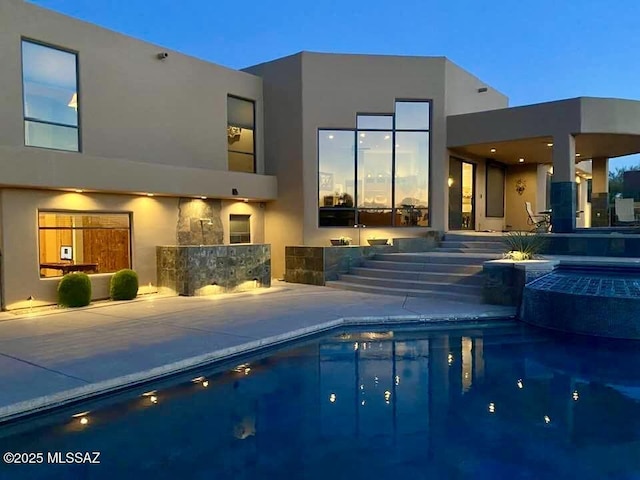 back of property featuring a patio, stucco siding, and a pool with connected hot tub