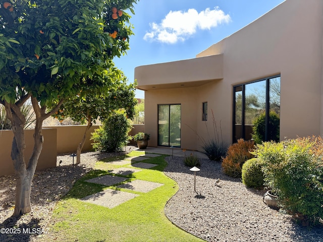 rear view of house featuring stucco siding and fence