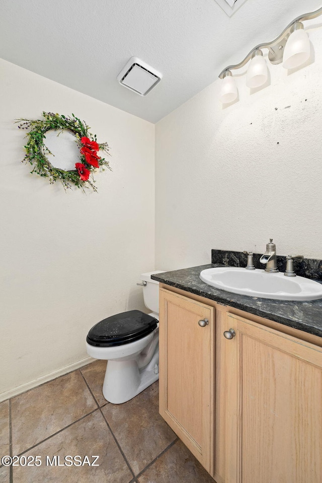 half bathroom featuring toilet, vanity, tile patterned floors, and a textured ceiling