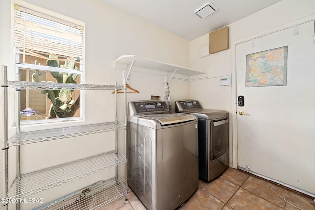 clothes washing area with washing machine and dryer, visible vents, and laundry area
