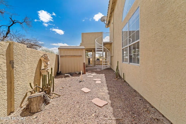 view of yard featuring stairs, an outbuilding, a storage shed, and fence