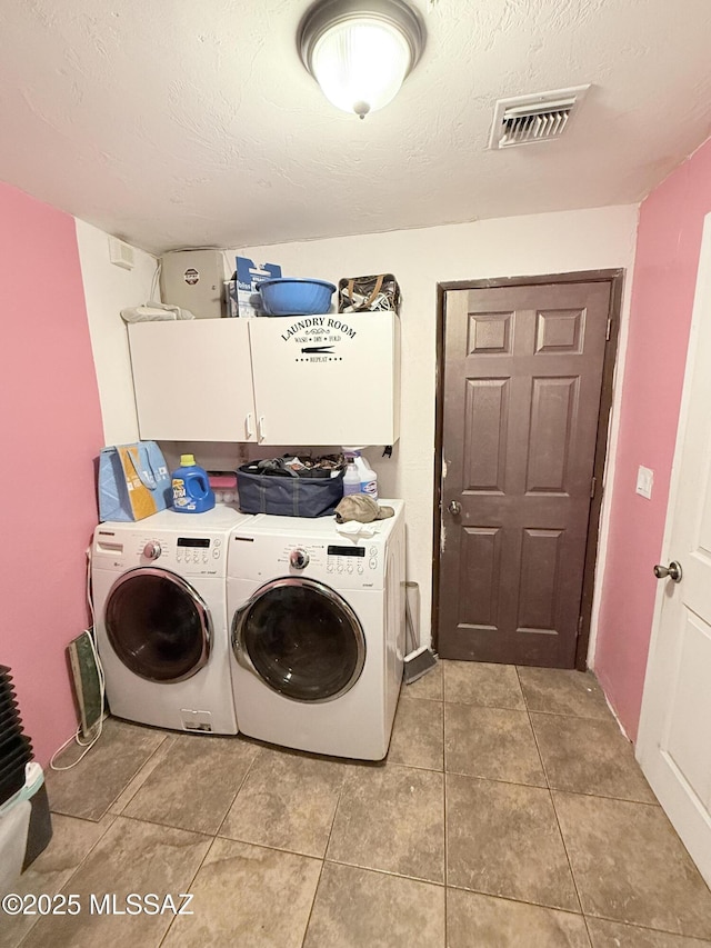 washroom with a textured ceiling, visible vents, washing machine and dryer, cabinet space, and light tile patterned floors