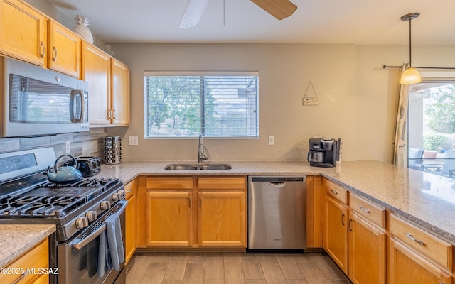 kitchen featuring light wood-style flooring, ceiling fan, stainless steel appliances, tasteful backsplash, and a sink